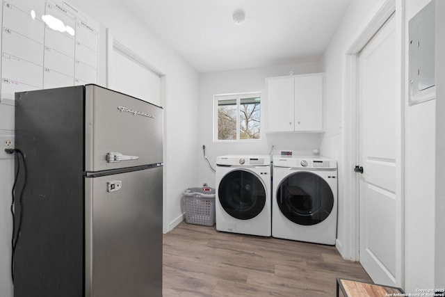 washroom featuring washer and dryer, hardwood / wood-style floors, and cabinets