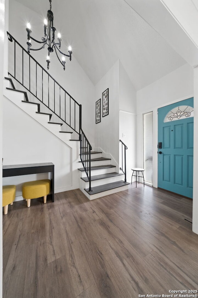 foyer with dark wood-type flooring, high vaulted ceiling, and an inviting chandelier