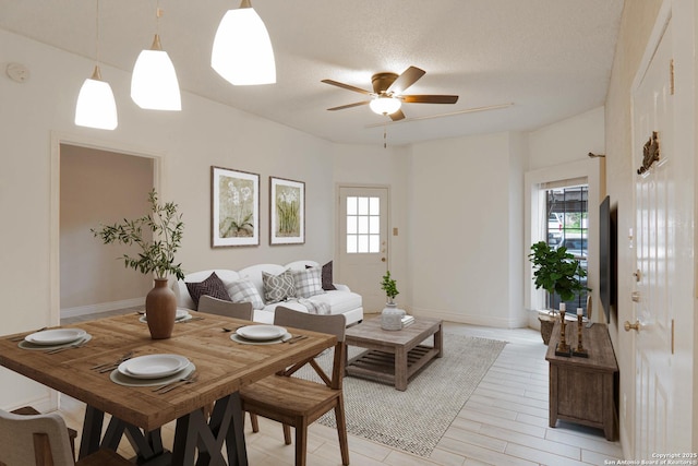 living room with ceiling fan, a textured ceiling, and light wood-type flooring