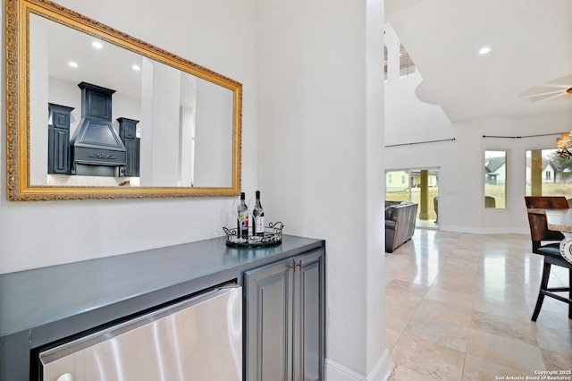 bar with ceiling fan, custom range hood, and a towering ceiling