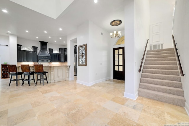 kitchen featuring a high ceiling, custom range hood, a chandelier, and a kitchen breakfast bar