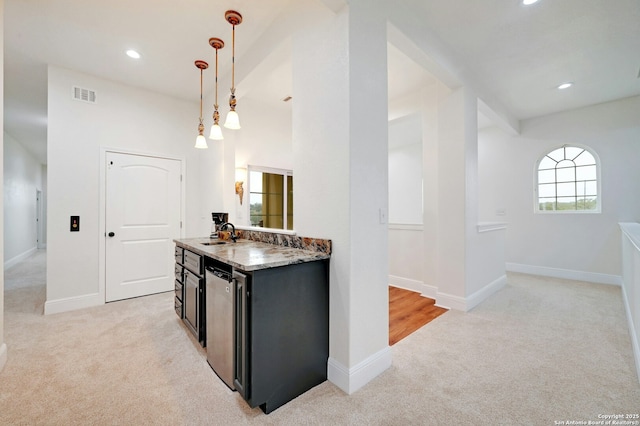 kitchen featuring light stone countertops, sink, pendant lighting, and light colored carpet