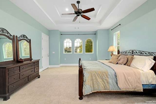 bedroom with light colored carpet, ceiling fan, and a tray ceiling