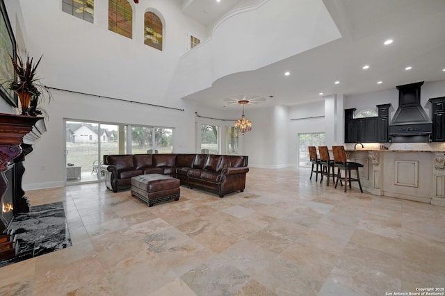 living room with a notable chandelier, a towering ceiling, and a premium fireplace