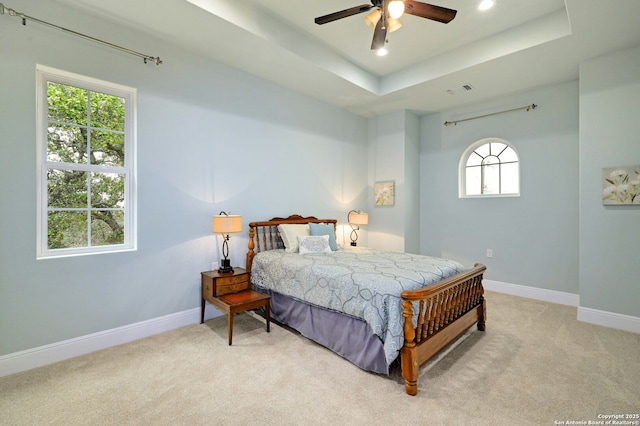 carpeted bedroom with a tray ceiling and ceiling fan