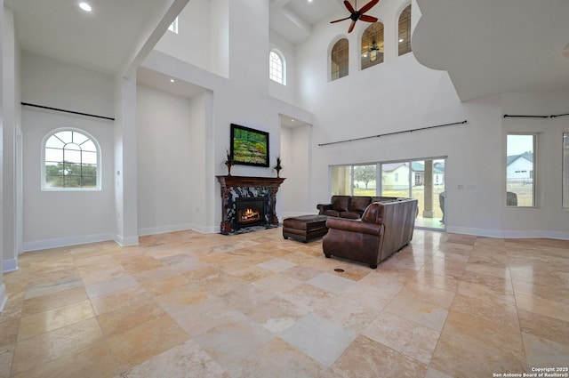 living room featuring a premium fireplace, a wealth of natural light, and ceiling fan