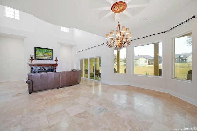 living room with coffered ceiling, a towering ceiling, a high end fireplace, and a chandelier