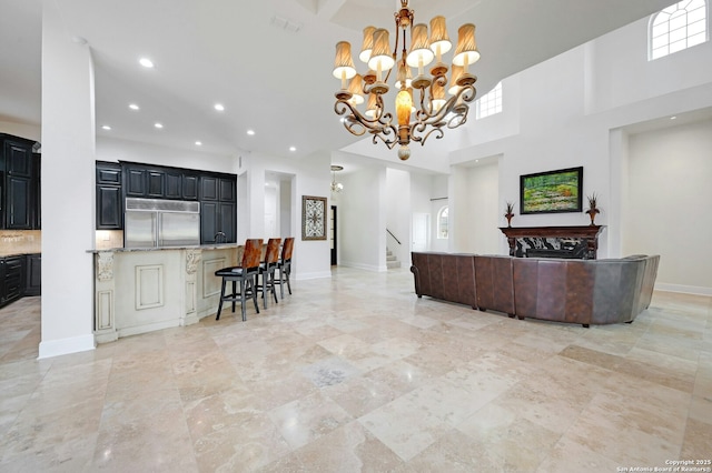 kitchen featuring a towering ceiling, stainless steel built in refrigerator, and a notable chandelier