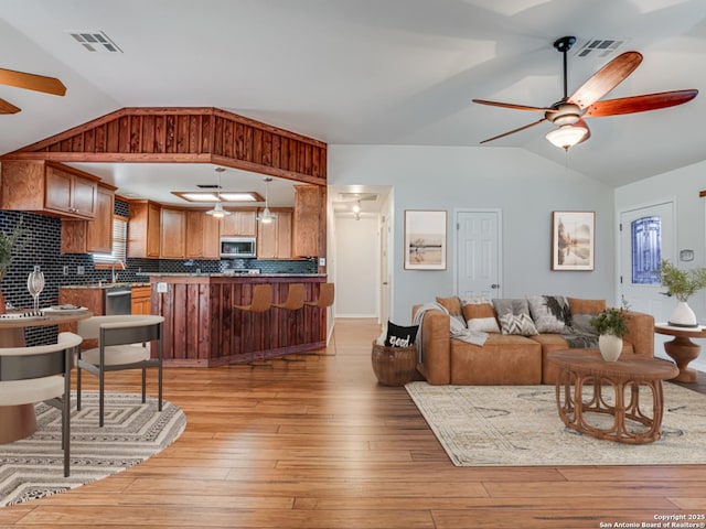 living room with ceiling fan, lofted ceiling, and light wood-type flooring