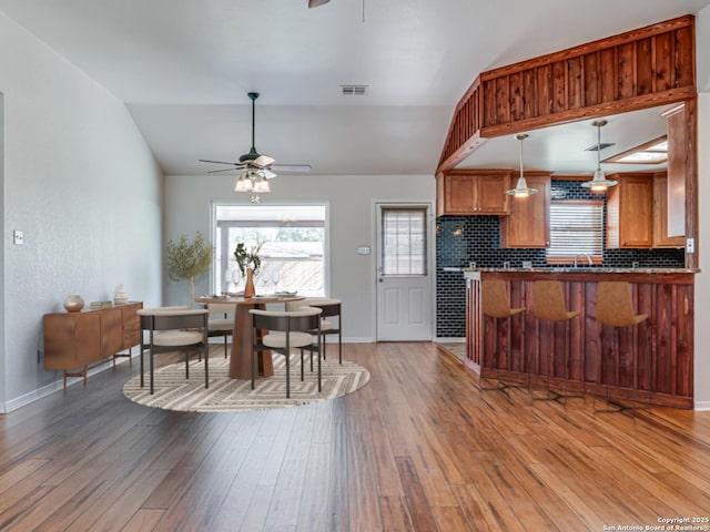 dining room with wood-type flooring, vaulted ceiling, and ceiling fan