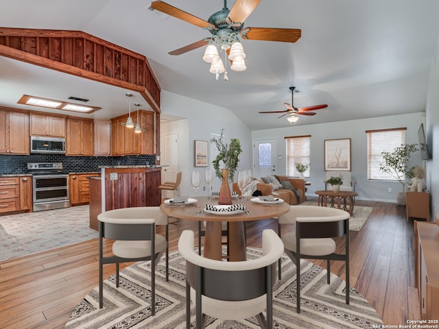 dining area with lofted ceiling and light wood-type flooring