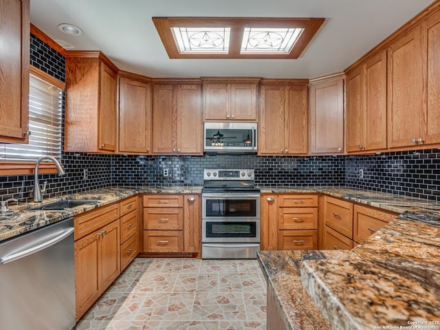 kitchen with tasteful backsplash, sink, stainless steel appliances, and stone countertops