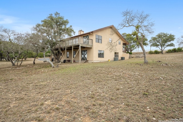 back of house with a deck, a yard, a chimney, and stucco siding