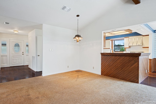 interior space with vaulted ceiling, dark carpet, visible vents, and baseboards