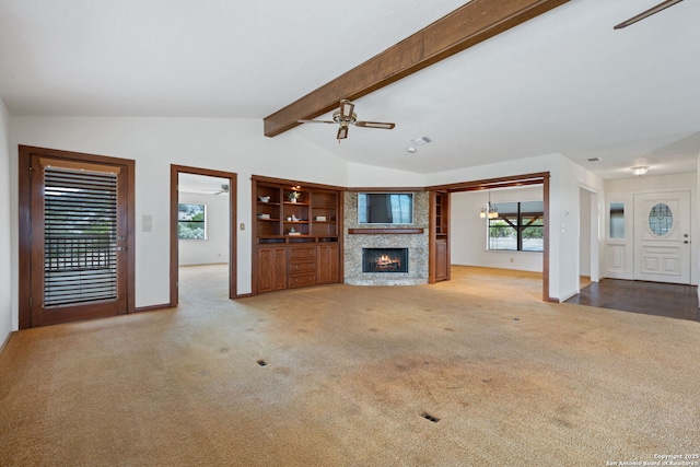 unfurnished living room with vaulted ceiling with beams, a ceiling fan, carpet flooring, a lit fireplace, and baseboards