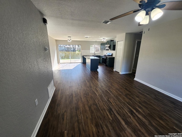 kitchen featuring visible vents, a kitchen island, open floor plan, dark wood-style flooring, and a textured ceiling