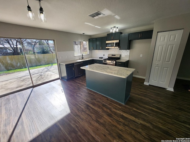 kitchen with dark wood finished floors, a kitchen island, hanging light fixtures, light stone countertops, and stainless steel appliances