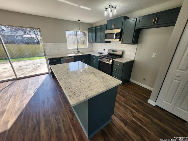 kitchen with light stone counters, a center island, dark wood finished floors, hanging light fixtures, and appliances with stainless steel finishes