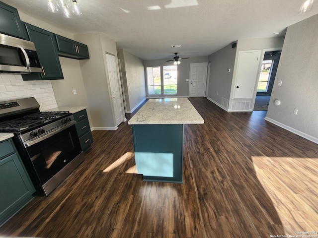 kitchen with dark wood-style floors, stainless steel appliances, a kitchen island, light stone countertops, and plenty of natural light