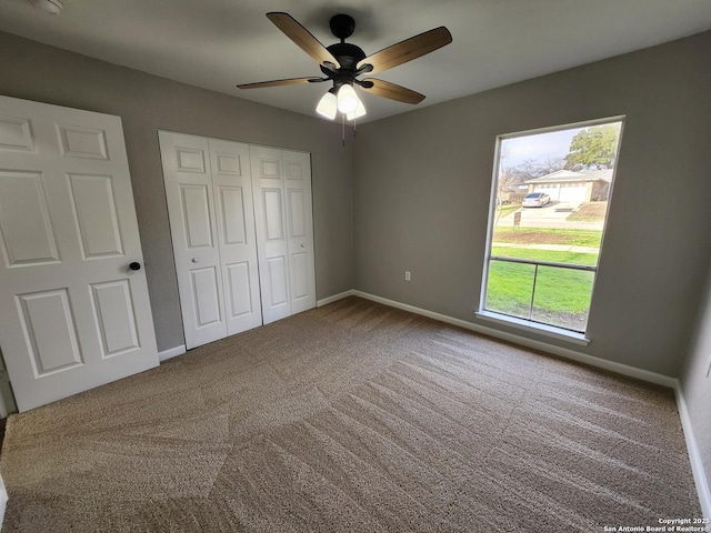 unfurnished bedroom featuring carpet, a closet, ceiling fan, and baseboards