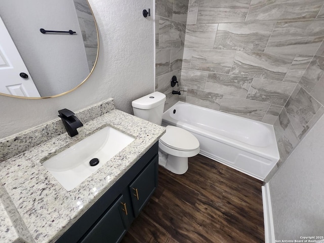 full bath featuring a textured wall, toilet, vanity, wood finished floors, and shower / bathtub combination