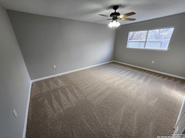 carpeted spare room featuring ceiling fan and baseboards