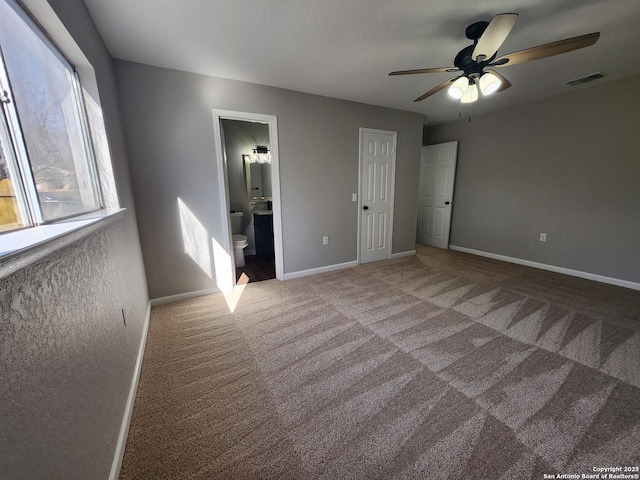 unfurnished bedroom featuring baseboards, visible vents, carpet flooring, and ensuite bathroom