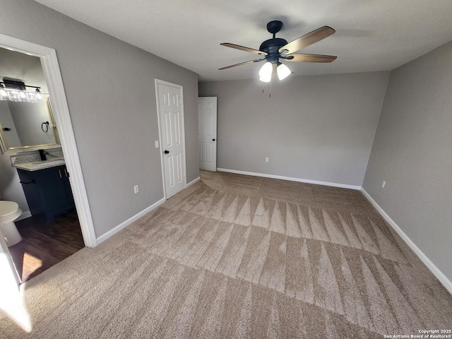 unfurnished bedroom featuring carpet floors, connected bathroom, baseboards, and a ceiling fan