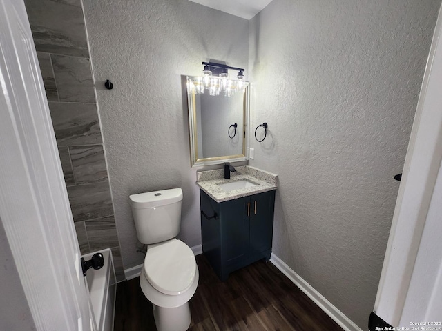 bathroom featuring vanity, baseboards, wood finished floors, and a textured wall