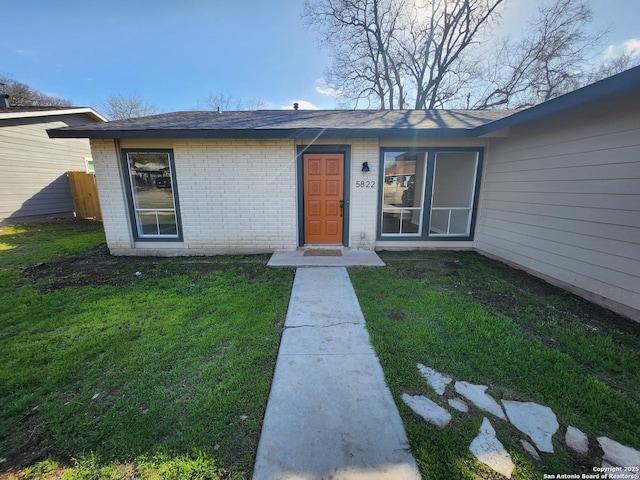 doorway to property featuring brick siding and a yard