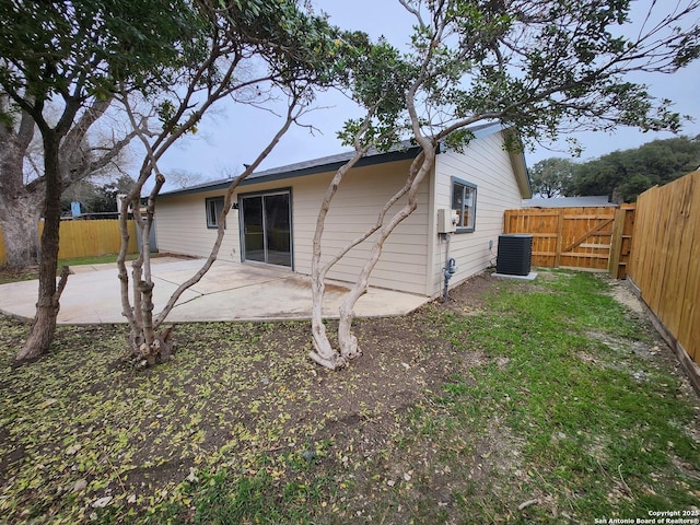 rear view of property featuring central AC, a patio area, fence, and a gate