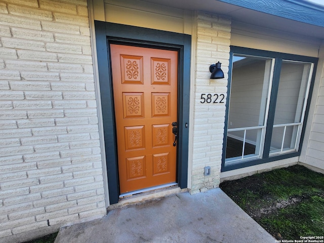 doorway to property featuring brick siding