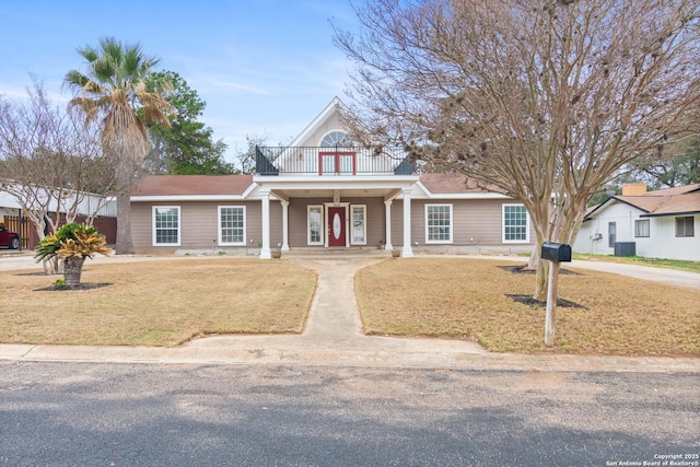 view of front of home with a balcony, covered porch, a front lawn, and central air condition unit