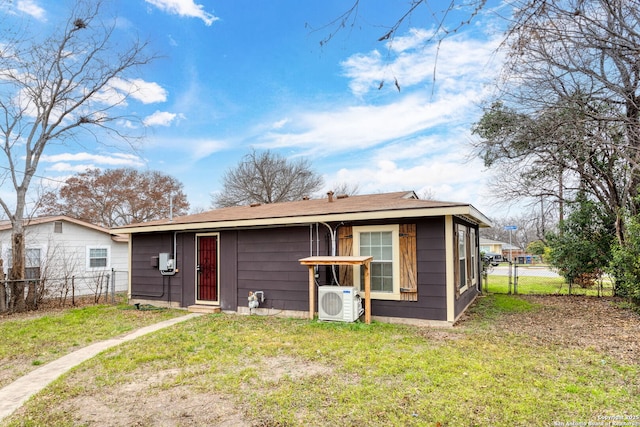 rear view of property featuring ac unit and a lawn