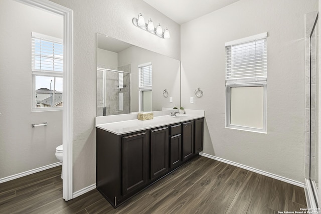 bathroom with hardwood / wood-style flooring, vanity, an enclosed shower, and toilet
