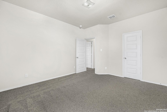 empty room featuring dark carpet and a textured ceiling