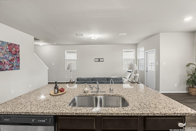kitchen featuring sink, dishwasher, a kitchen island with sink, dark hardwood / wood-style floors, and light stone countertops