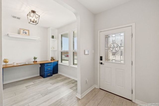 foyer featuring light wood-type flooring, visible vents, arched walkways, and baseboards