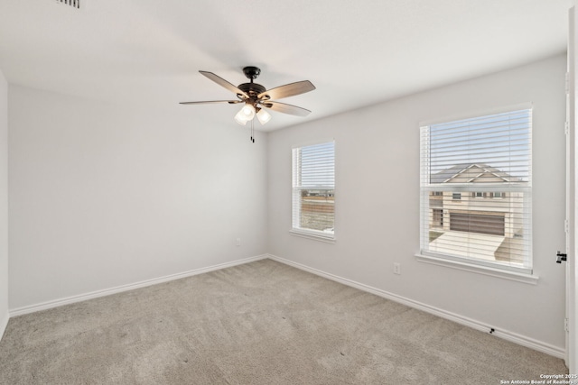 empty room with a ceiling fan, light colored carpet, and baseboards