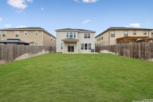 back of property with a fenced backyard and a lawn