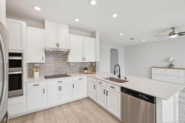 kitchen featuring a peninsula, a sink, white cabinets, light countertops, and appliances with stainless steel finishes