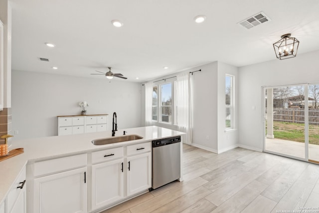 kitchen featuring visible vents, light countertops, stainless steel dishwasher, white cabinetry, and a sink