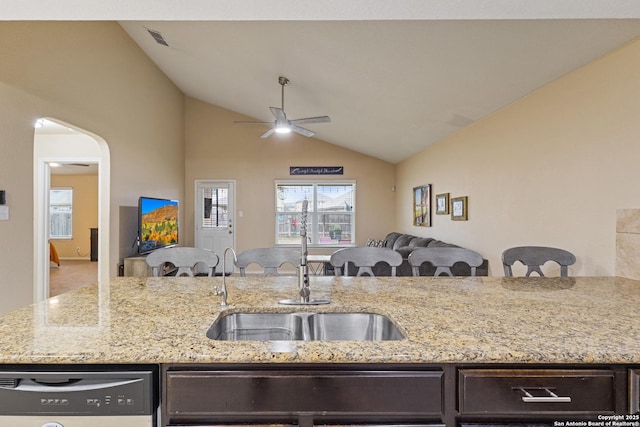 kitchen with dishwashing machine, sink, light stone counters, and vaulted ceiling