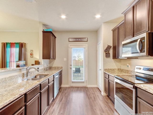 kitchen featuring light stone counters, appliances with stainless steel finishes, sink, and light wood-type flooring