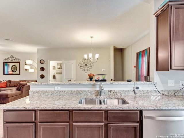 kitchen with sink, a chandelier, hanging light fixtures, dishwasher, and light stone countertops