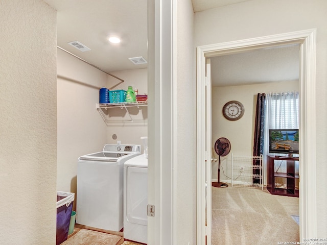 laundry area with washer and clothes dryer and light colored carpet