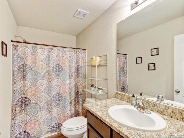 bathroom featuring vanity, a textured ceiling, and toilet