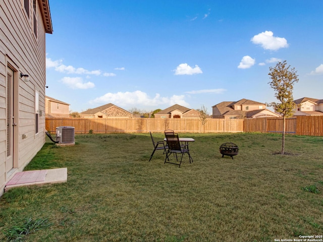 view of yard with central AC and an outdoor fire pit