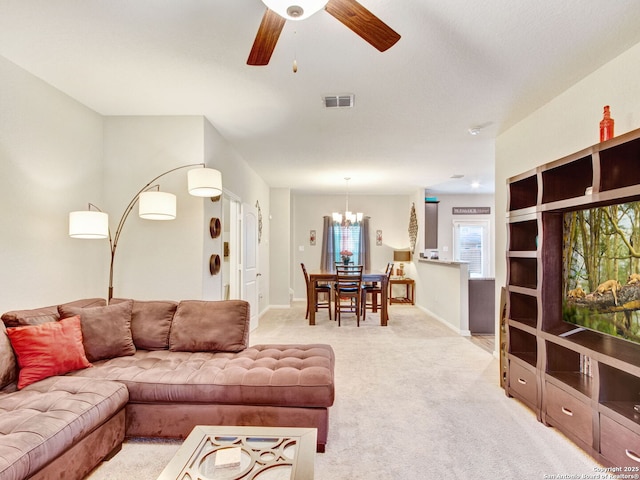 carpeted living room featuring ceiling fan with notable chandelier