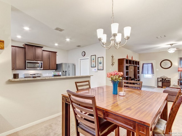 dining room with ceiling fan with notable chandelier and light colored carpet